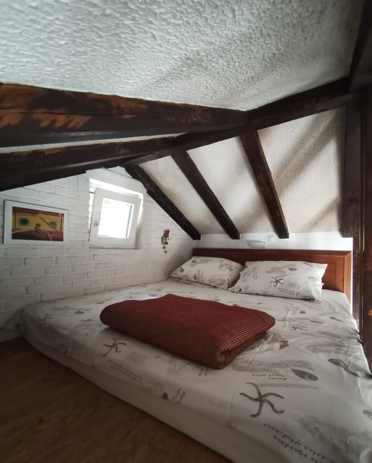 Loft bedroom with double bed under beams