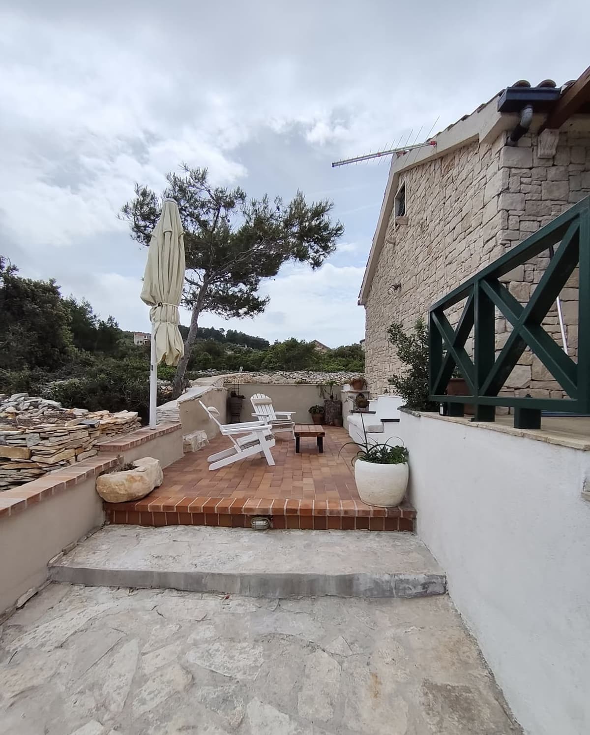 Side terrace with white chairs and parasol